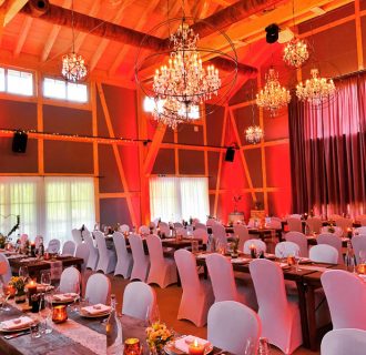 Hochzeits DJ René Pera in der Holsteins Mühle/Nümbrecht. Blick auf die gedeckten Tische zum Dinner. Der Raum erstrahlt in amber rot.