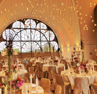 Professioneller DJ René Pera bei einer exklusiven Hochzeitsfeier im Dachsalon/Flora/Köln. Der Raum ist amber gold gefärbt. Die Tische sind festlich gedeckt. Von der Decke hängen Plexiglaskugeln herunter.