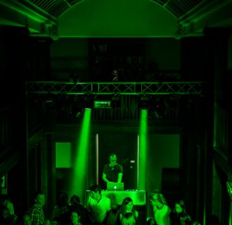 Professioneller Event DJ René Pera bei einer Party im Neptunbad/Köln. Man blickt von oben auf die volle Tanzfläche mit grünem Licht.
