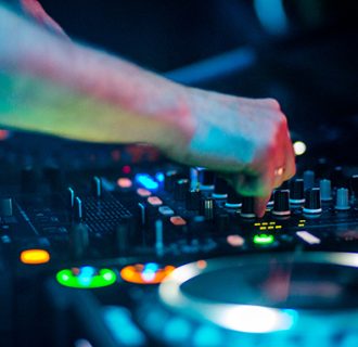 DJ René Pera bei der Aufnahme eines DJ-Audiomixes "Die richtige Musik zur richtigen Zeit" am DJ-Pult. Er dreht an den Knöpfen des DJ-Mixers.